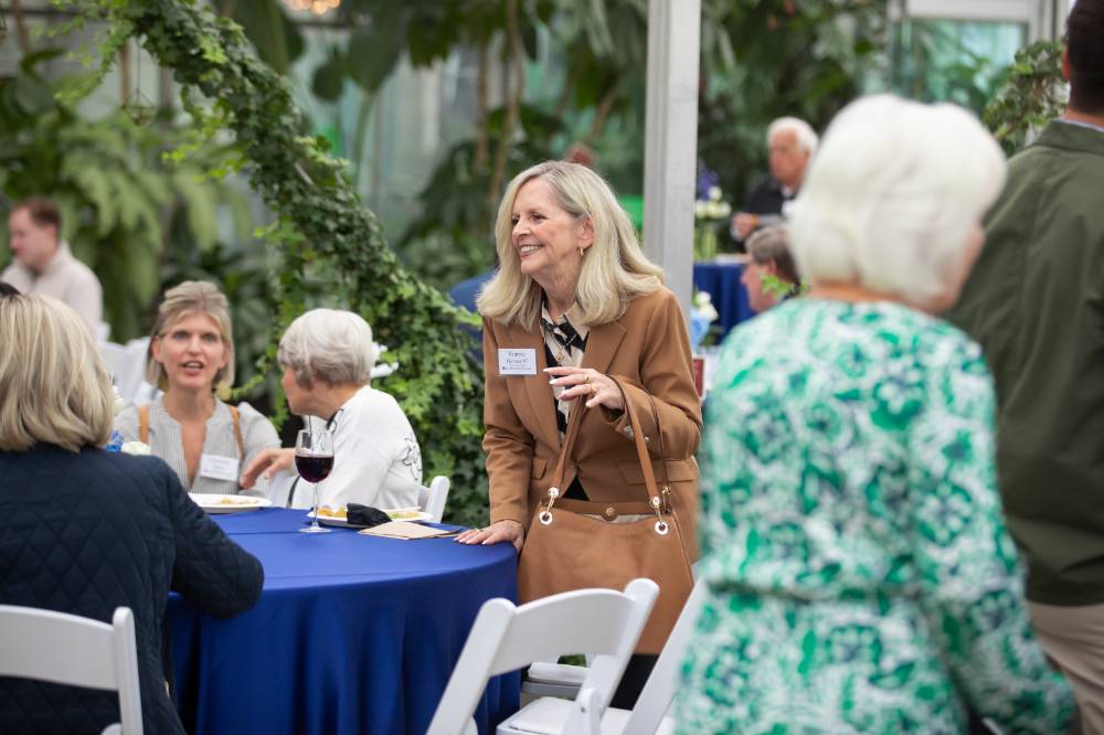 Vonnie Herrera standing with hand on table, smiling at someone off camera